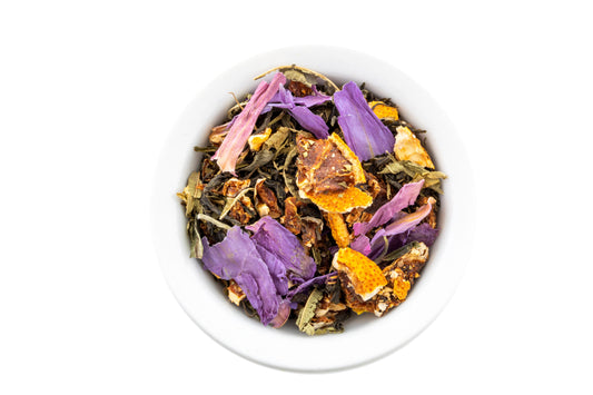 Chinese green tea blended with colorful flowers and dehydrated fruits in a white bowl on a white background