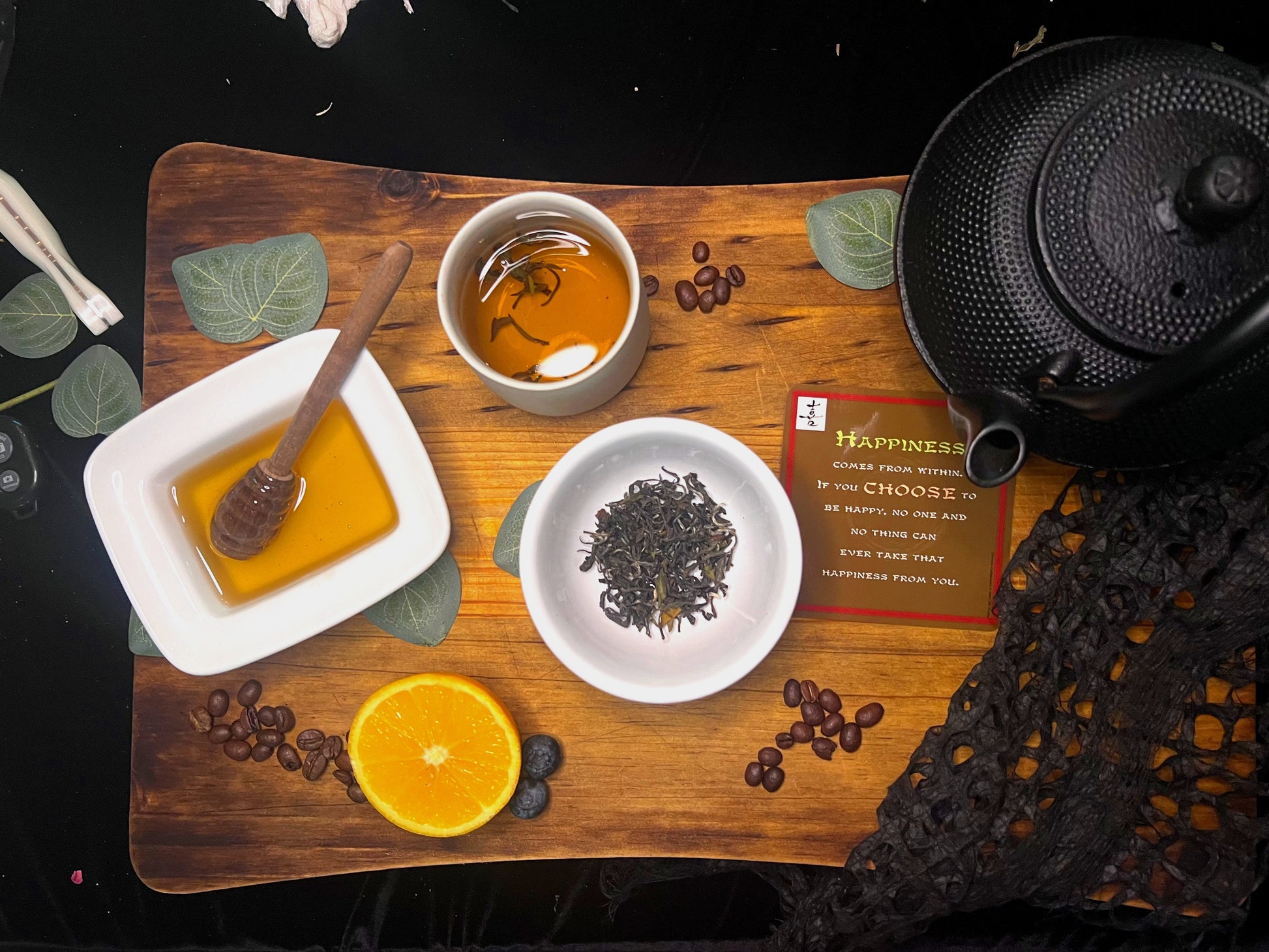 Lac Hong Oolong tea-making setup with oolong tea leaves, honey, orange, and teapot on a wooden board.