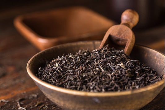 Wooden bowl filled with Korean partially oxidized tea leaves on a wooden surface