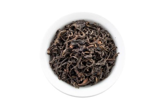 Dry smoked oolong leaves in a white bowl on a white background