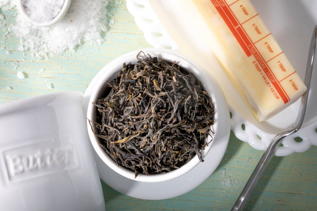 Loose leaf Gross National Happiness Bhutanese green tea from Samcholing, displayed in a white ceramic bowl against a soft sage green background.