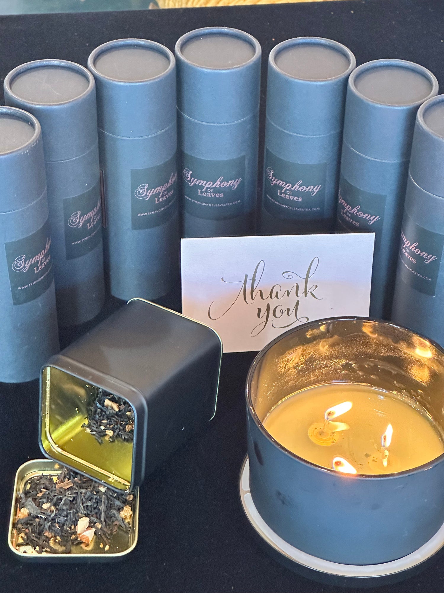 six canisters and a candle with tea blend displayed