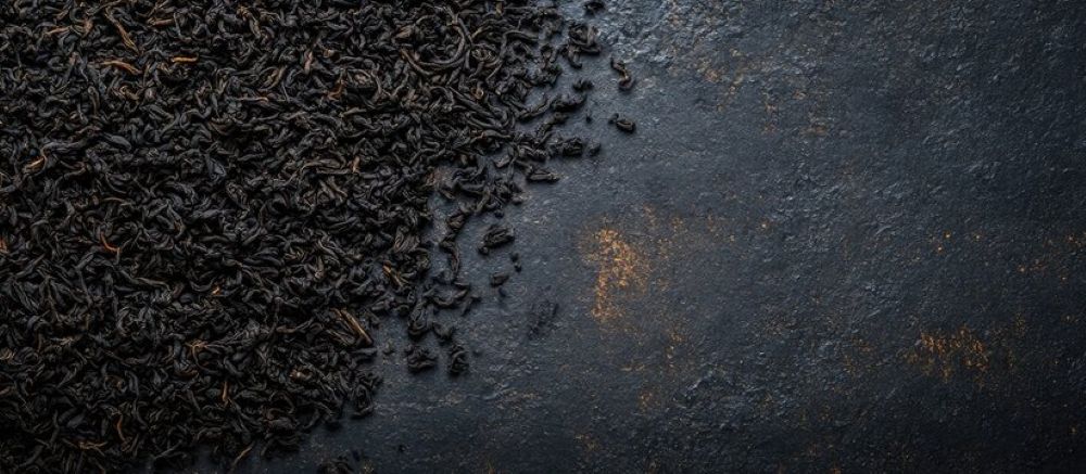 Black loose leaf teas on a smoke gray board.