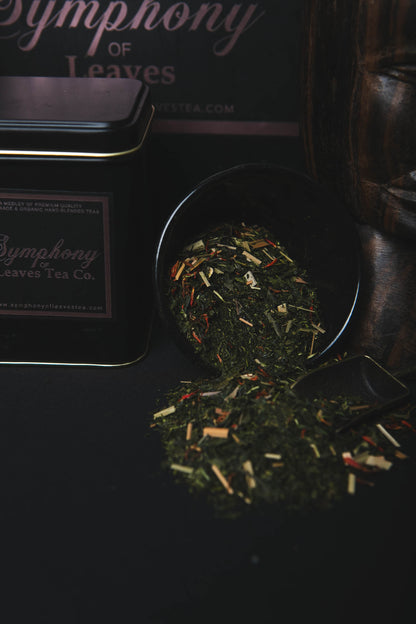 Japanese green leaves blended with safflower and lemongrass in a black scoop with 'Symphony of Leaves Tea Co.' tea canister in the background