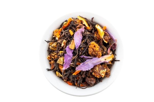 Loose leaf Black Indian tea leaves with flowers and herbs in a white bowl on a white background
