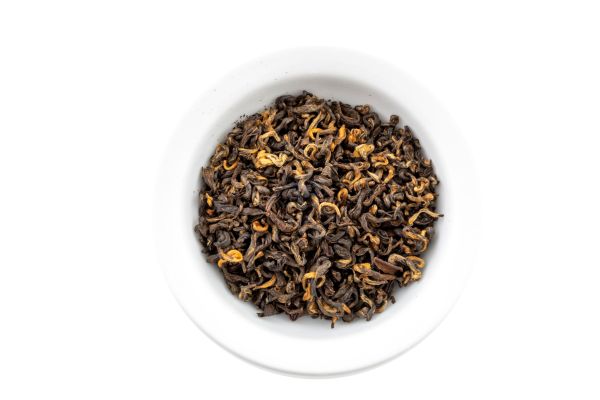 Dry Himalayan Golden black tea leaves in a white bowl on a white background
