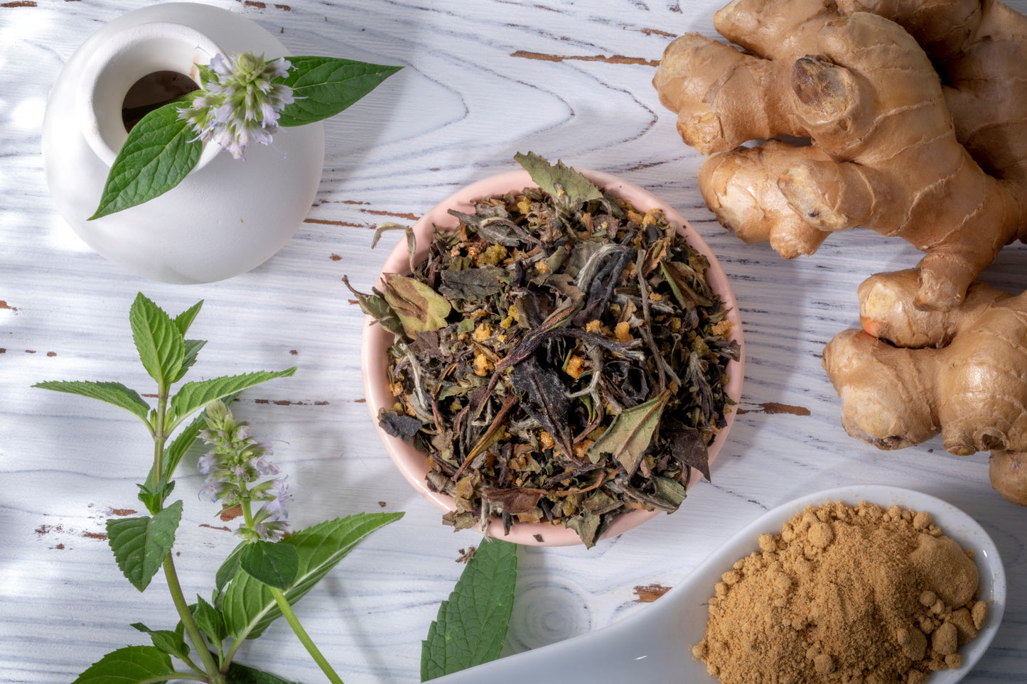 White peony tea, blended with ginger, sage, and basil, along side a vase, fresh ginger and ground cumin