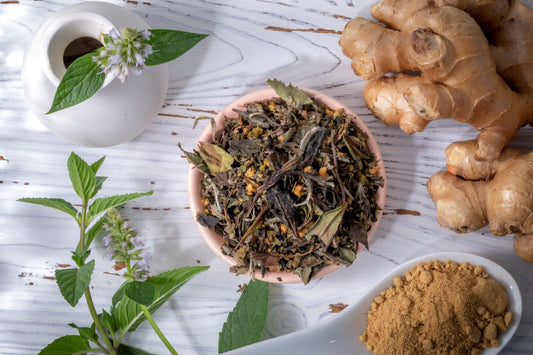 White peony tea, blended with ginger, sage, and basil, along side a vase, fresh ginger and ground cumin