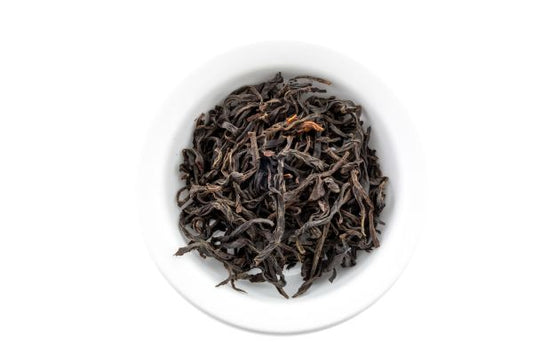 Chinese Dry black tea leaves in a white bowl on a white background