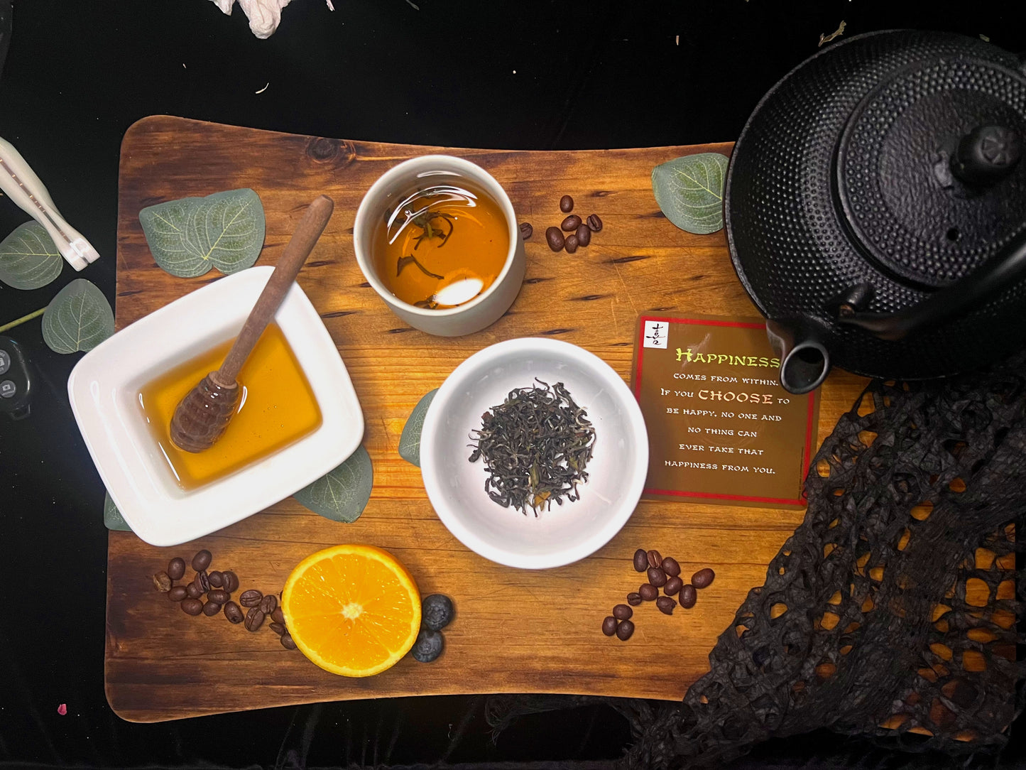 Lac Hong Oolong tea-making setup with oolong tea leaves, honey, orange, and teapot on a wooden board.
