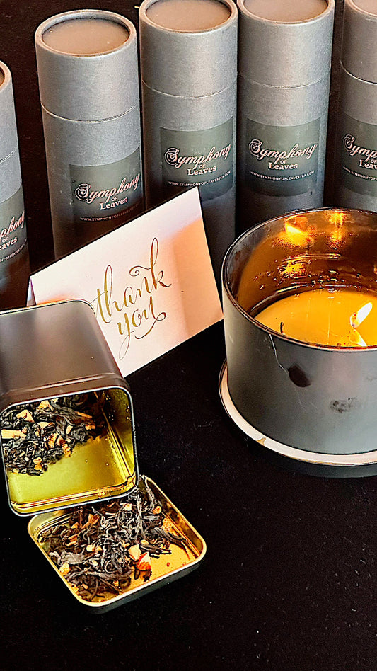 Branded Symphony of Leaves tea packaging with open tin showing tea leaves and a card, set against a dark background.