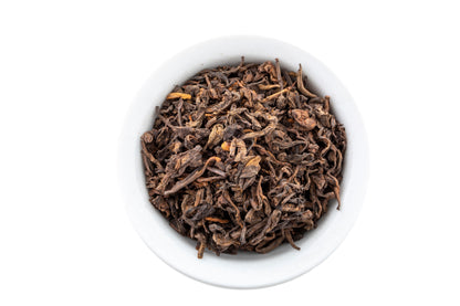 Dry Pu-erh tea leaves in a white bowl on a white background