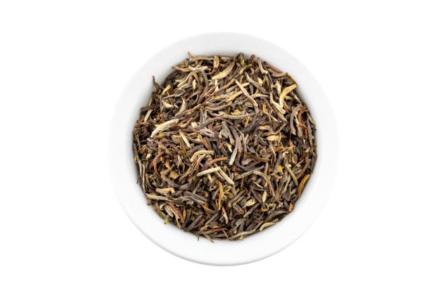 Dry Thai oolong tea leaves in a white bowl on a white background