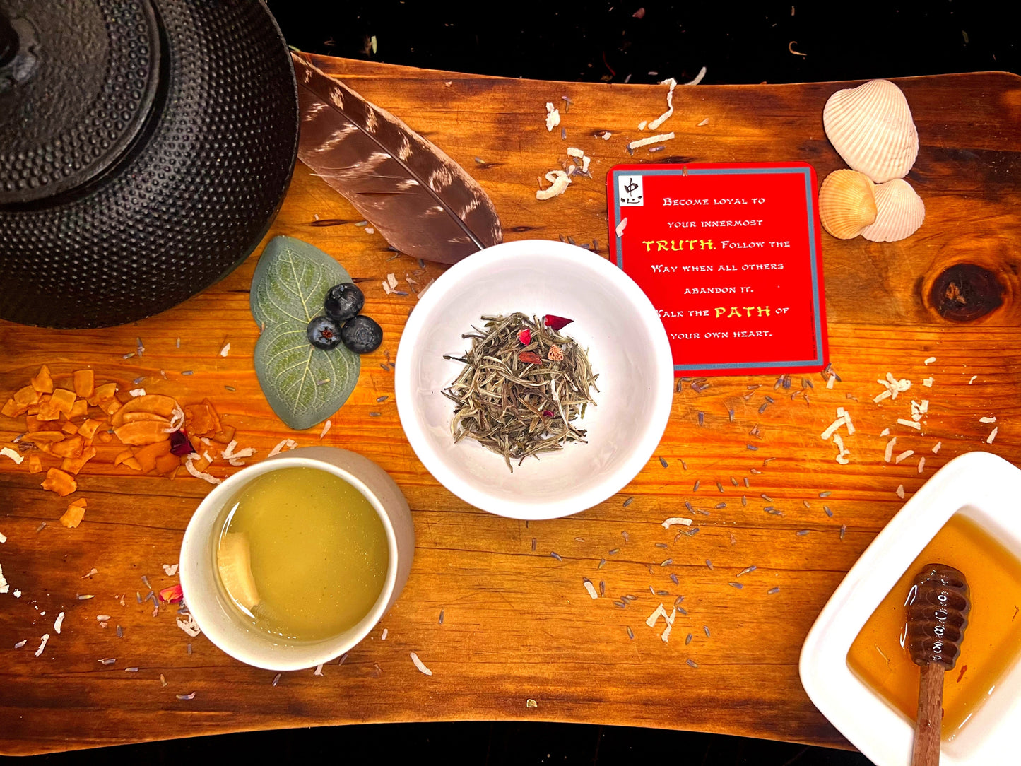 Tea-preparation with a cup of white Vietnamese loose tea, organic honey, and an inspirational card on a wooden board.