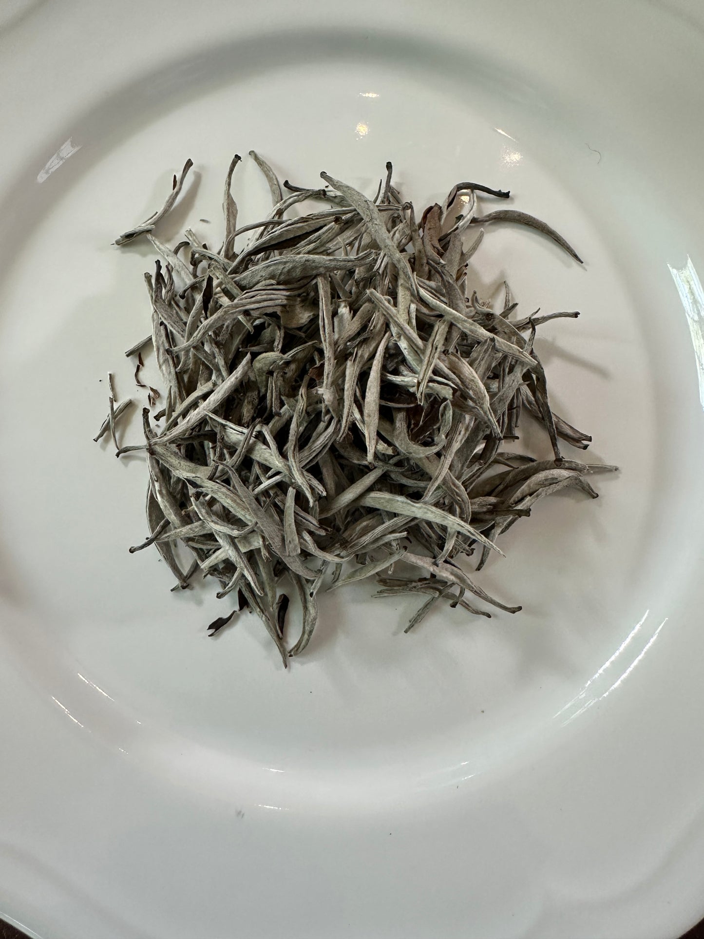 Dry Vietnamese white loose leaf tea leaves on a white plate