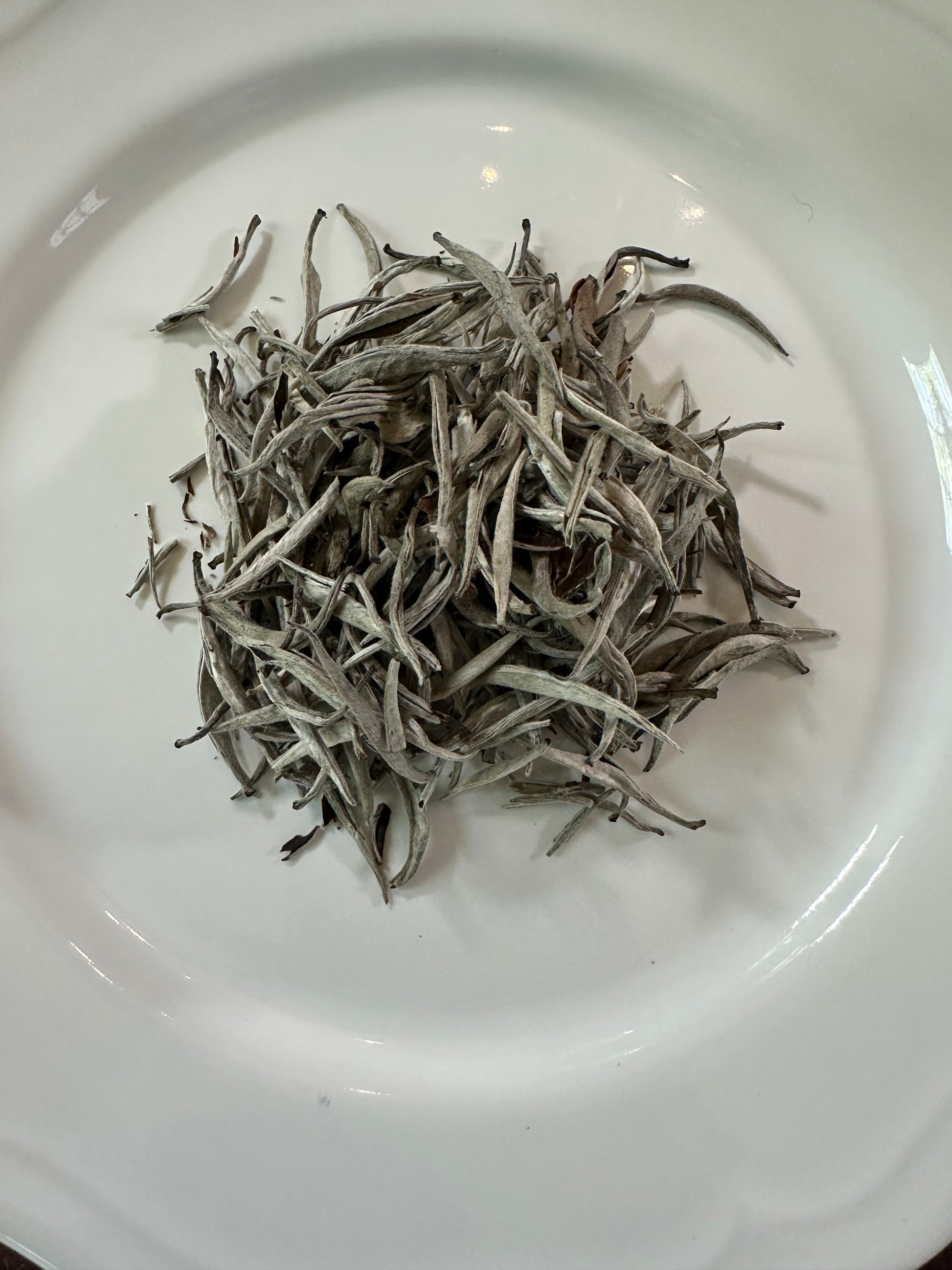 Dry Vietnamese white loose leaf tea leaves on a white plate