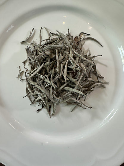 Dry Vietnamese white loose leaf tea leaves on a white plate