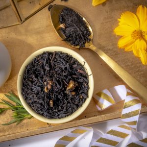 Black tea leaves with golden spoon and flowers