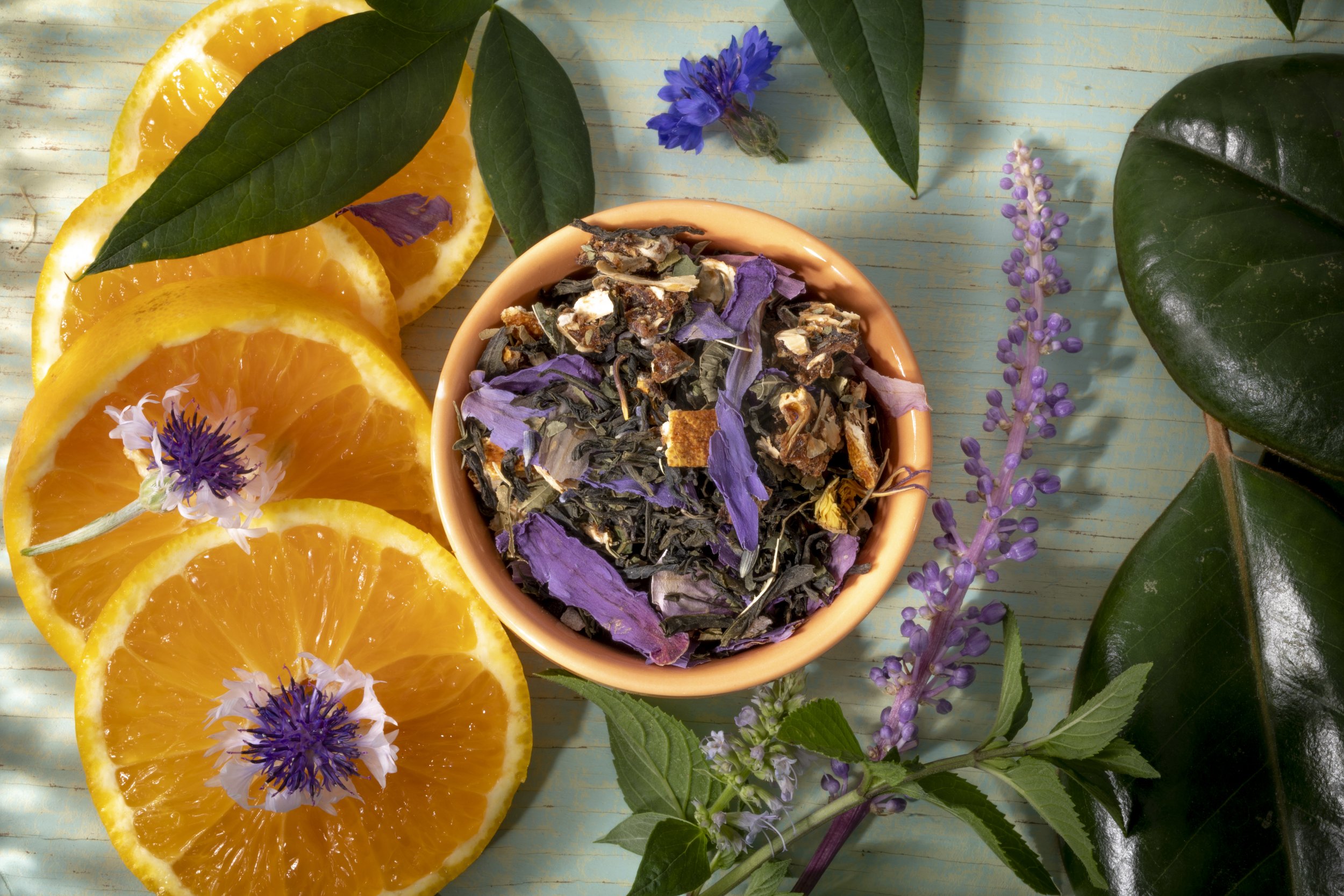 Herbal tea blend with orange slices and flowers.