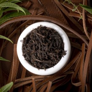 Bowl of black tea with green leaves