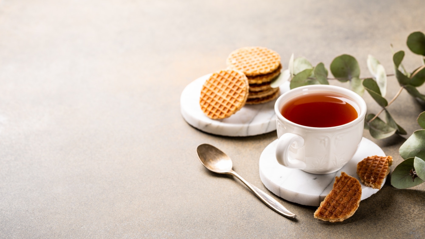 Cup of tea with waffles and spoon.