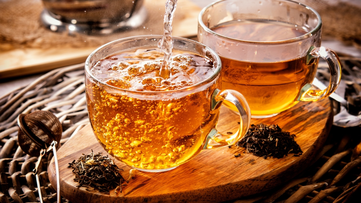 Pouring tea into glass mugs on table