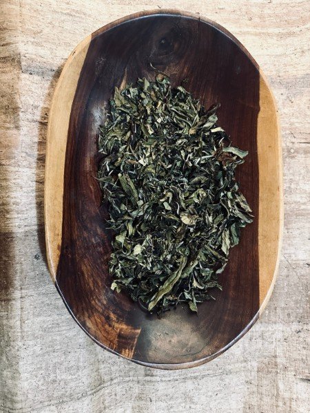 Dried green leaves in wooden dish display.