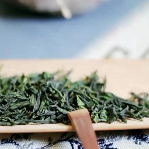 Dried green tea leaves on wooden plate