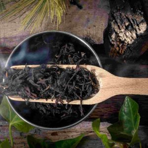 Steaming black tea leaves with wooden scoop