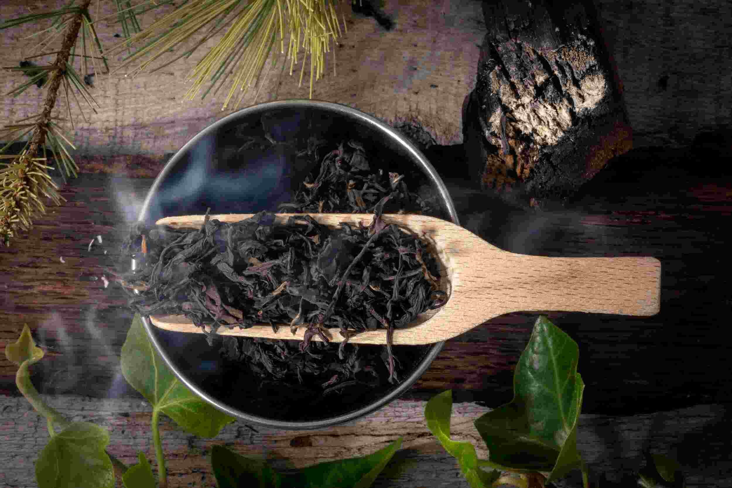 Steaming black tea leaves with wooden scoop