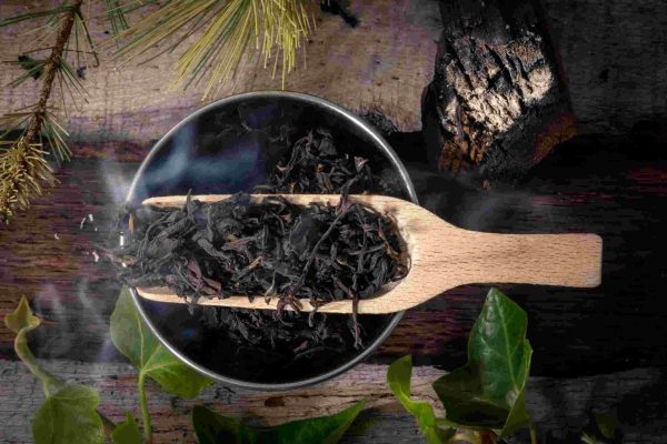 Wooden scoop with dried black tea leaves steaming