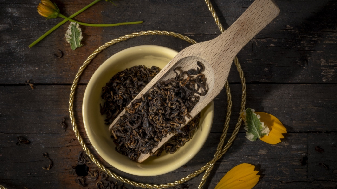 Aromatic black tea leaves in wooden scoop