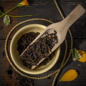 Aromatic black tea leaves in wooden scoop