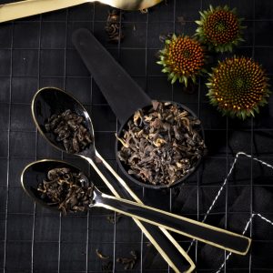 Black tea leaves and spoons on grid tray