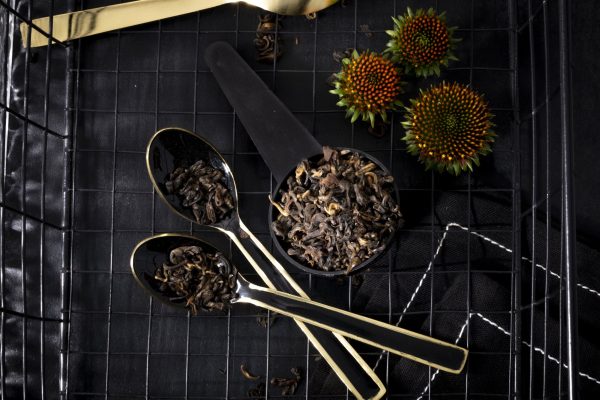 Black tea leaves and spoons on grid tray