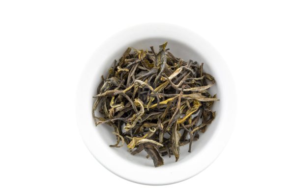 Dry green tea leaves in white bowl