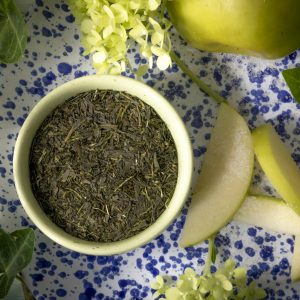 Green tea leaves with sliced apples and flowers.