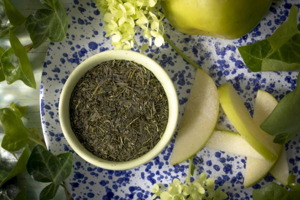 Green tea leaves with sliced apples and flowers.