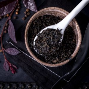 Dark loose tea leaves in ceramic bowl spoon