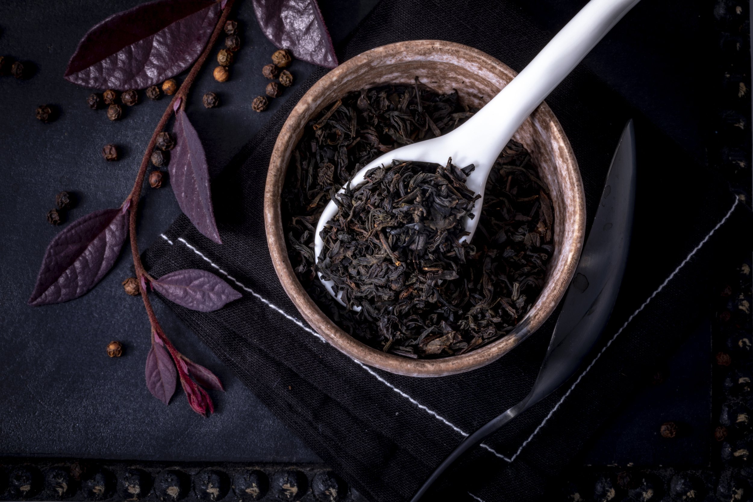 Dark loose tea leaves in ceramic bowl spoon