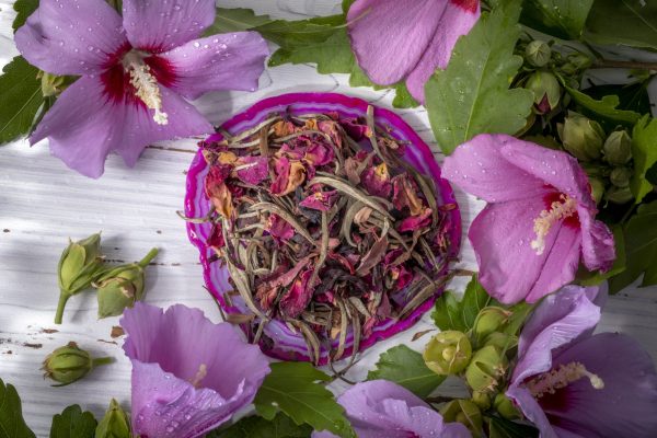 Tea leaves surrounded by vibrant pink flowers