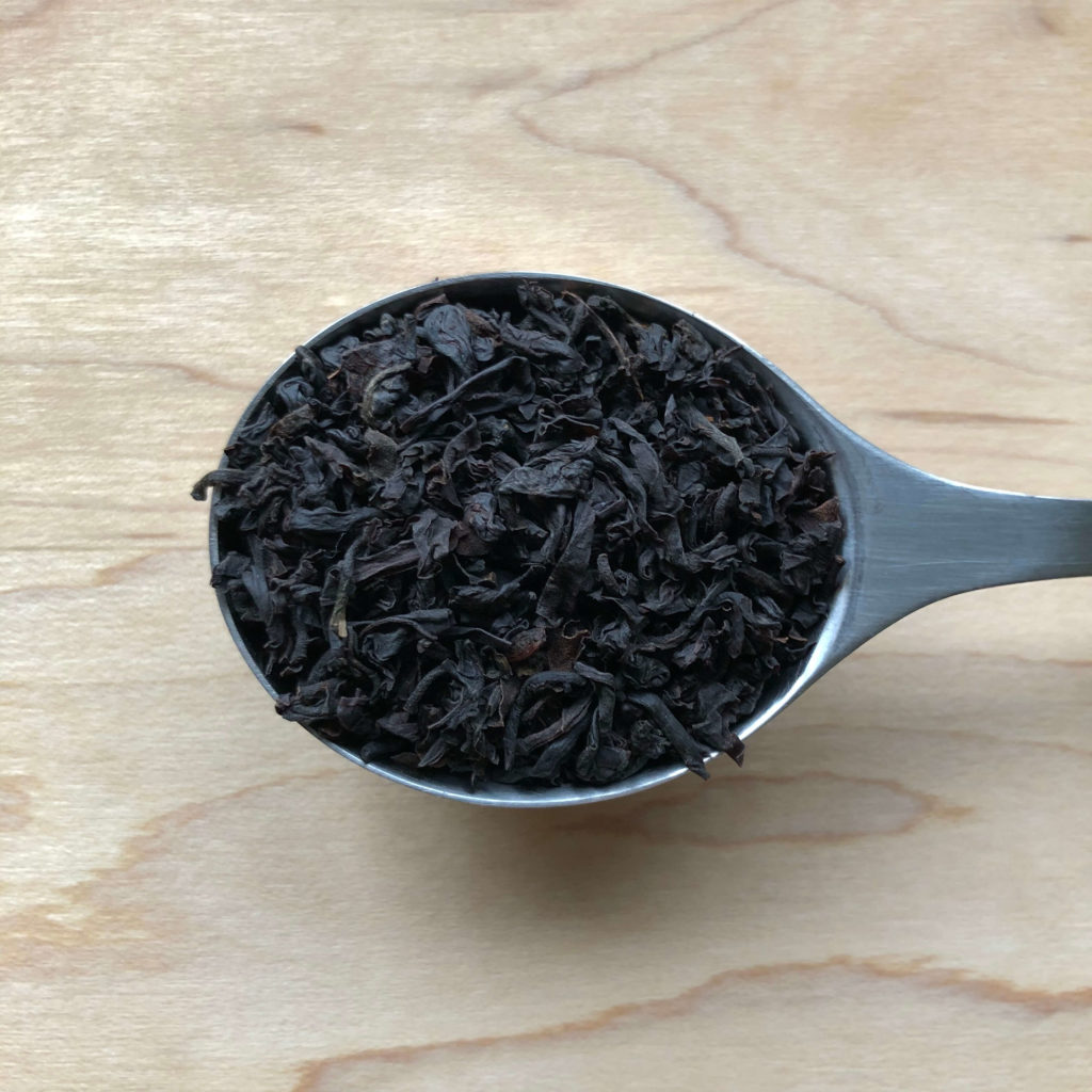 Spoonful of loose leaf black tea on wood