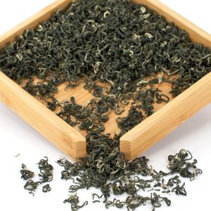 Loose black tea leaves in wooden tray