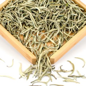 Loose white tea leaves in wooden tray