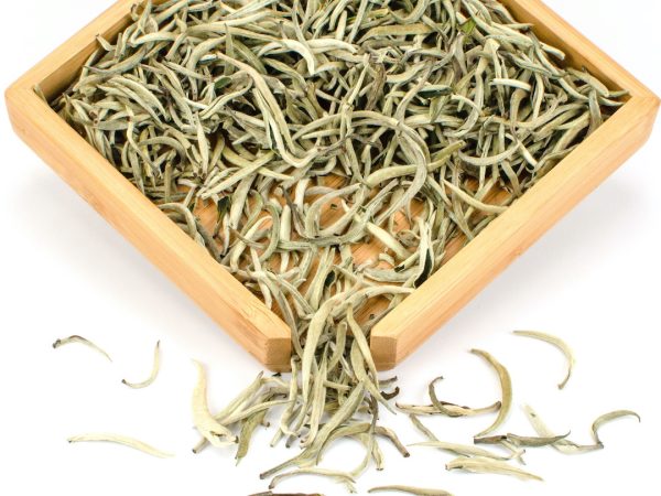 Loose white tea leaves in wooden tray