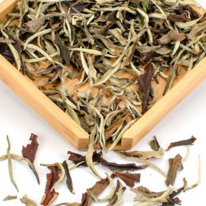 Loose white tea leaves in wooden tray.