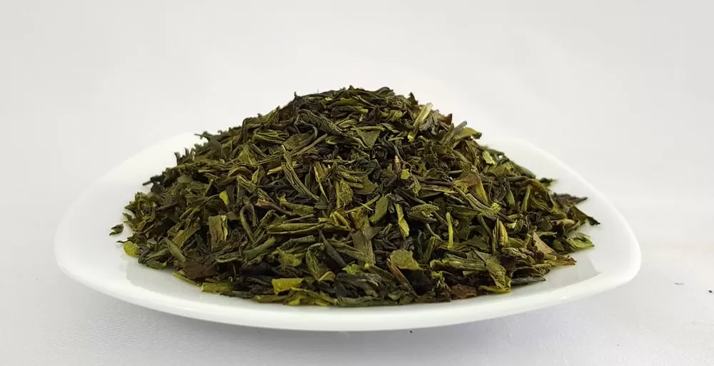 Dried green tea leaves on white plate